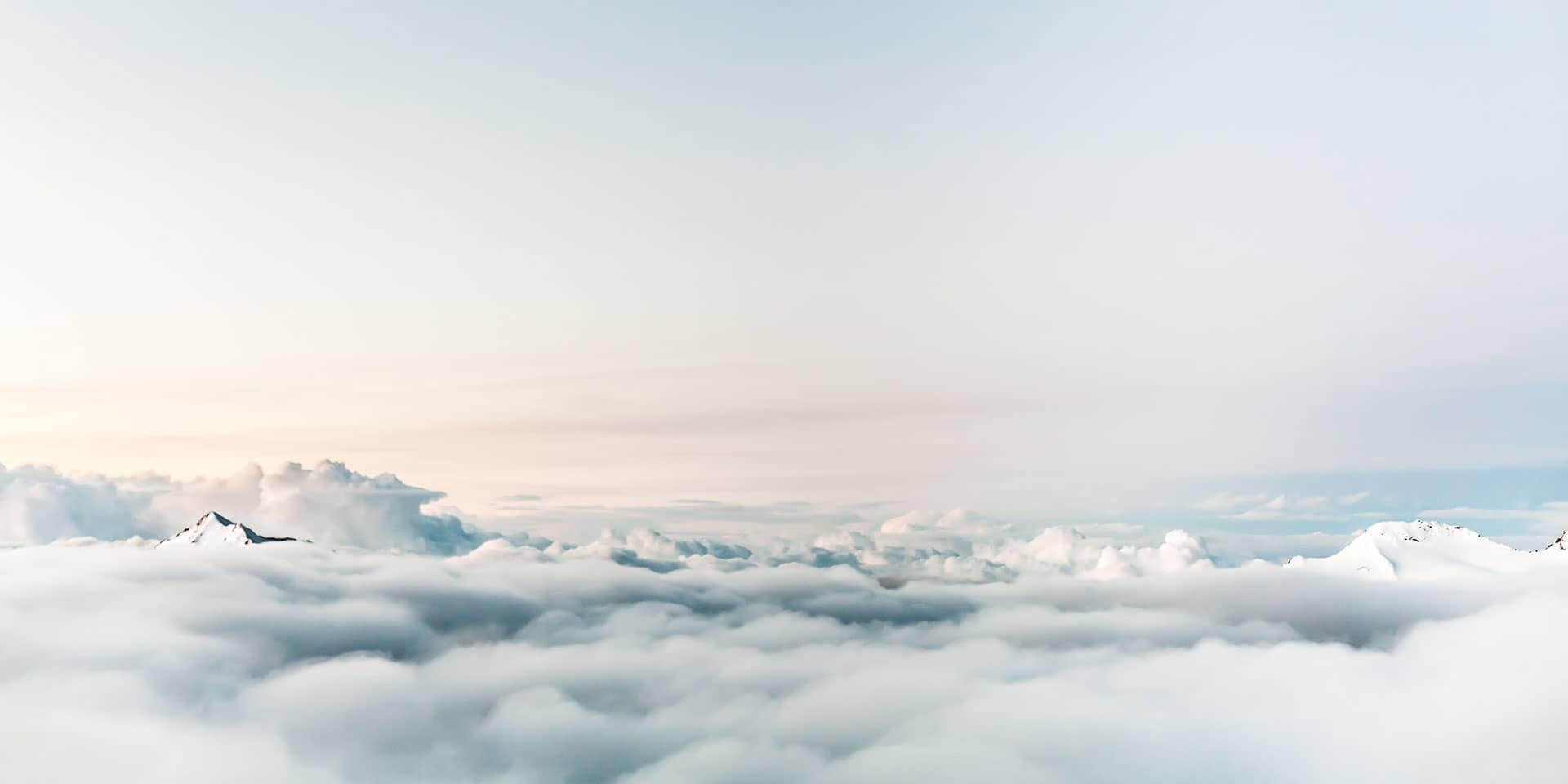 Luftaufnahme über den Wolken mit einer Bergspitze sichtbar bei Sonnenschein